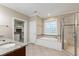 Well-lit bathroom with dual sinks, soaking tub, and separate tiled shower at 4517 Gates St, Raleigh, NC 27609