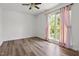 Bright bedroom features a ceiling fan, laminate flooring and large window with pink curtains at 5105 Baywood Forest Dr, Knightdale, NC 27545