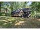 Rear exterior view of two-story home with deck, wooded surroundings, dark siding, and roof at 5217 West Oaks Dr, Fuquay Varina, NC 27526