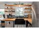 Sunlit kitchen with a stainless steel refrigerator, black farmhouse sink, and lovely open wooden shelving at 73 Lynnville Ct, Lillington, NC 27546