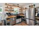 Cozy kitchen with a stainless steel refrigerator, farmhouse sink, and beautiful open wooden shelving at 73 Lynnville Ct, Lillington, NC 27546