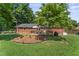 View of the brick home's backyard with a lovely deck and beautiful landscaping at 908 Clarion Dr, Durham, NC 27705