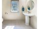 Bathroom with pedestal sink, round mirror, tile floors, and natural light at 101 Painted Rock Ct, Garner, NC 27529