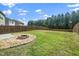 Large backyard with wooden fence and fire pit surrounded by green grass and trees at 1022 Homecoming Way, Durham, NC 27703