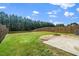 A spacious fenced backyard features a grassy lawn, mature trees and a gravel fire pit area at 1022 Homecoming Way, Durham, NC 27703