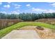 A spacious fenced backyard features a grassy lawn, mature trees and a gravel fire pit area at 1022 Homecoming Way, Durham, NC 27703