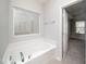 A bright bathroom features a soaking tub underneath a patterned glass window and an open door to the bedroom at 1022 Homecoming Way, Durham, NC 27703