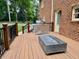 A wooden deck featuring a rectangular gas burning fire pit, stainless steel grill and brick exterior wall at 105 Abbotsford Ct, Durham, NC 27712