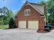 A two-car garage sits at the end of a pristine driveway, beside a brick home and green landscape at 105 Abbotsford Ct, Durham, NC 27712