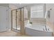 Bright bathroom features a tiled shower, soaking tub, and decorative window at 120 Silver Bluff St, Holly Springs, NC 27540