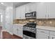 Well-lit kitchen with stainless steel appliances, granite counters, tile backsplash, and white cabinets at 120 Silver Bluff St, Holly Springs, NC 27540