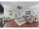 Bright living room with hardwood floors, a ceiling fan, a fireplace, a comfortable sofa, and natural light at 120 Silver Bluff St, Holly Springs, NC 27540
