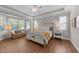 Bright main bedroom with tray ceilings, hardwood flooring, a ceiling fan, and a cozy sitting area at 120 Silver Bluff St, Holly Springs, NC 27540