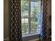 A large window with decorative curtains offers a view of the outside greenery at 121 Brentfield Loop, Morrisville, NC 27560