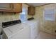 Laundry room features cabinets for storage, floral wallpaper, and side by side washer and dryer at 124 Jack Bennett Rd, Chapel Hill, NC 27517