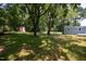 Overgrown backyard featuring a lawn, mature trees, and various storage buildings at 1344 Highland Dr, Wake Forest, NC 27587