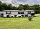 Charming single-story home with a well-maintained lawn, complemented by lush trees and a carport at 1404 N N Nc Hwy 87, Elon, NC 27244