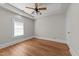 Bedroom featuring a ceiling fan, tray ceilings, hardwood floors, white trim, and a window at 1600 Pineview St, Raleigh, NC 27608
