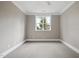 This bedroom features neutral paint and carpet, white trim, and a bright window at 1600 Sweetwater Ln, Raleigh, NC 27610