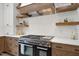 Close up of the kitchen stove with a custom wood vent hood and floating shelves at 1600 Sweetwater Ln, Raleigh, NC 27610