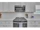 Modern kitchen featuring white cabinets, stainless steel appliances, and a white subway tile backsplash at 175 Steep Rock Dr, Willow Springs, NC 27592
