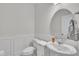 Stylish powder room with white wainscoting, pedestal sink, round mirror, and modern fixtures at 175 Steep Rock Dr, Willow Springs, NC 27592