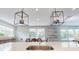 Close-up of kitchen island sink with modern lighting; dining area visible in the background, with an outside view at 1880 Woodall Crest Dr, Apex, NC 27502