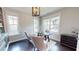 Bright office with stylish furnishings, including a dark wood desk and a chandelier, complemented by natural light from the windows at 1880 Woodall Crest Dr, Apex, NC 27502