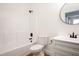 Bright white bathroom with a shower-tub combo, toilet, and vanity with black fixtures at 205 Gentry St, Roxboro, NC 27573