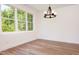 Empty room with hardwood floors and a rustic chandelier next to a large bank of windows at 205 Gentry St, Roxboro, NC 27573