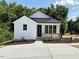 Charming white home with a black metal roof, wooden porch, and well-manicured lawn at 205 Gentry St, Roxboro, NC 27573