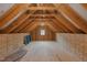 Unfinished attic space with exposed wooden beams and a window, offering potential for customization at 2511 Range Overlook Xing, Apex, NC 27523