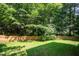 A large, green backyard, surrounded by a brown wooden fence and trees at 2613 Sweet Gum Dr, Hillsborough, NC 27278
