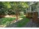 Well-maintained backyard featuring an elevated porch, green lawn, and mature trees at 2613 Sweet Gum Dr, Hillsborough, NC 27278