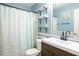 Bathroom features a white vanity, patterned shower curtain, shelves with decor, and black hardware at 326 Slate Dr, Gibsonville, NC 27249