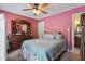 Cozy pink bedroom with a queen bed, ceiling fan, and a large wooden dresser with a mirror at 3573 Northern Estates Cir, Rocky Mount, NC 27804