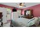 Bright pink bedroom featuring a queen bed, ceiling fan, and a large window with floral curtains at 3573 Northern Estates Cir, Rocky Mount, NC 27804