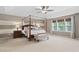Spacious main bedroom featuring a four-poster bed, ceiling fan, and large window with natural light at 3806 Stoneybrook Dr, Durham, NC 27705