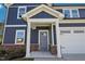 Close up of a navy two-story home showcasing a covered entryway and a two-car garage at 3813 Rosebush Dr, Zebulon, NC 27597