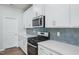 Bright kitchen features white cabinetry, stainless steel microwave, and a blue backsplash at 3813 Rosebush Dr, Zebulon, NC 27597
