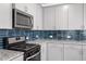 Well-equipped kitchen featuring granite countertops, gas range, and tile backsplash at 479 Clark Creek Ln, Cary, NC 27519