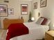 Bright bedroom with white bedding, red accents, dresser, and decorative artwork at 500 Umstead Dr # D307, Chapel Hill, NC 27516