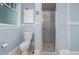 Bright bathroom with blue walls, a glass enclosed shower, and white porcelain toilet at 513 Cutler St, Raleigh, NC 27603