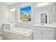 Bright bathroom featuring dual sinks, a soaking tub with tile surround, and large window at 5148 Glen Creek Trl, Garner, NC 27529