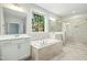 Bright bathroom featuring dual sinks, a soaking tub with tile surround, and a glass-enclosed shower at 5148 Glen Creek Trl, Garner, NC 27529