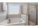 Bright bathroom featuring a tub with wood caddy and a glass door shower at 534 Lionheart Ln, Sanford, NC 27330