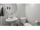 Cozy half-bath with a pedestal sink, round mirror, and modern fixtures, enhanced by neutral color palette at 534 Lionheart Ln, Sanford, NC 27330