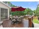 Spacious wooden deck with an outdoor dining set and an umbrella, surrounded by mature trees at 55 Fleming Forest Dr, Youngsville, NC 27596