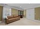 Comfortable living room featuring neutral carpet, tan leather sofa, and window with decorative curtains at 55 Fleming Forest Dr, Youngsville, NC 27596