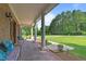 Covered porch with brick flooring, seating, and views of the landscaped yard and mature trees at 55 Fleming Forest Dr, Youngsville, NC 27596